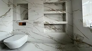 Luxurious marble-effect bathroom in Birkenhead featuring built-in shelves, a wall-hung toilet, and an elegant tile design.