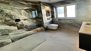 Contemporary bathroom in Heald Green featuring dramatic stone-effect walls, a walk-in shower, wall-hung toilet, and a sleek modern vanity.